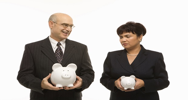 business people holding unequal size piggy banks equal pay 620x330
